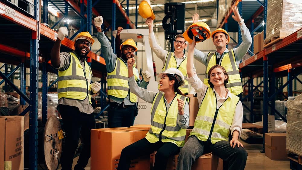 Group of warehouse workers in a warehouse, cheering.