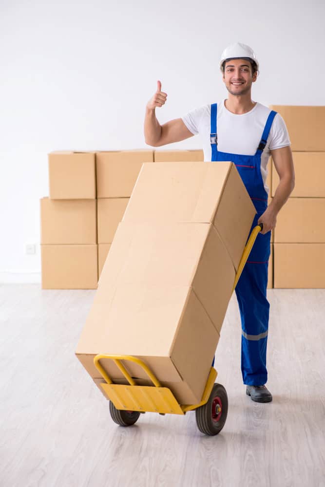 Man with boxes on a moving dolly smiling and giving a thumbs-up smiling.