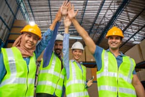 Stock picture of 4 warehouse workers doing a high-five gesture. 